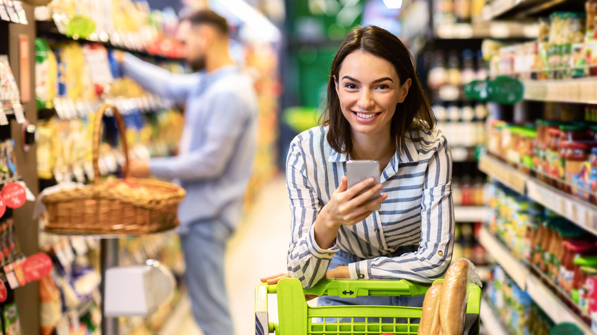 Young woman with mobile phone shopping in hypermarket