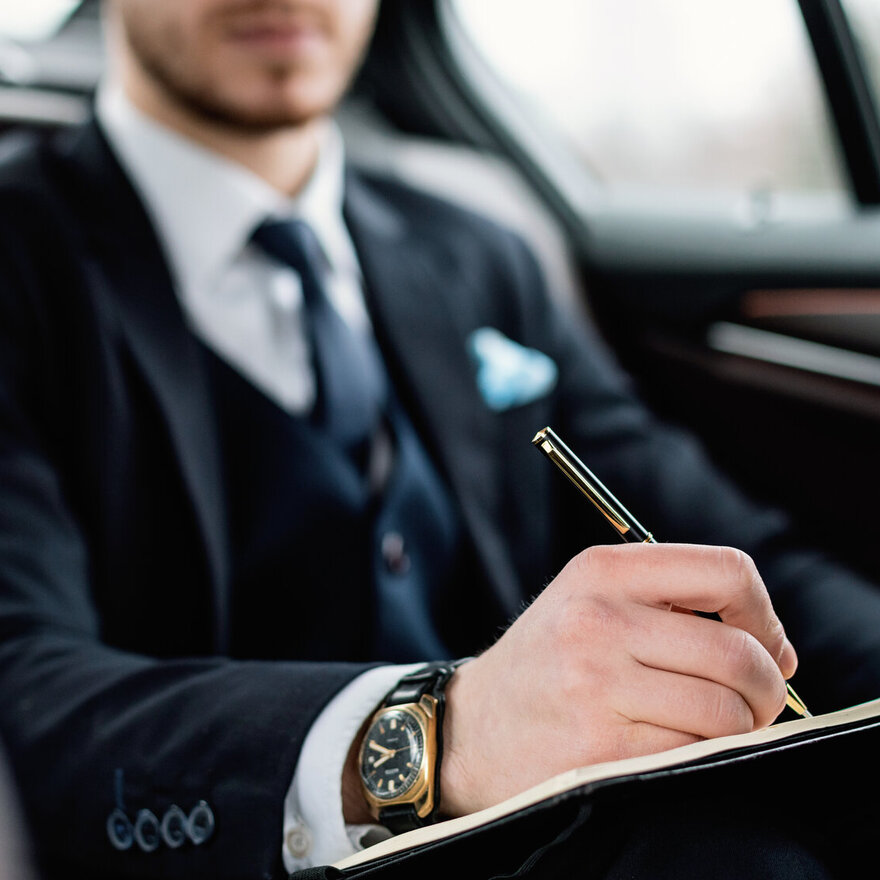 Young businessman writing in notebook in luxury car