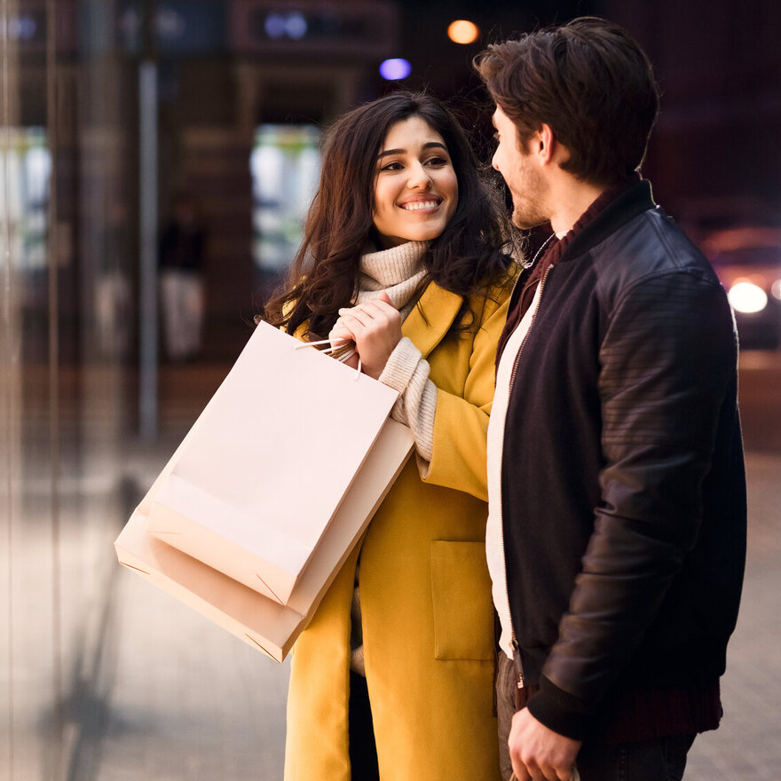 Woman asking boyfriend to buy clothes, standing near shop window