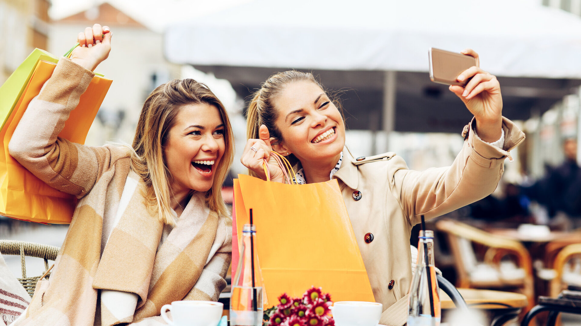Two women friends taking a selfie in cafe after shopping