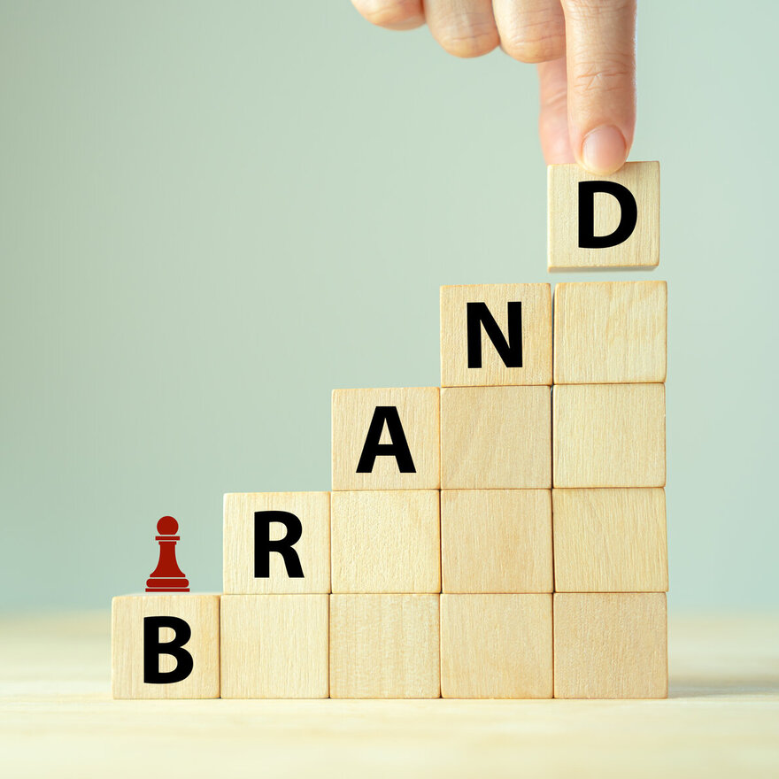 Brand strategy concept. Developing a strong brand strategy differentiate from competitors and build loyalty with customers. Wooden cube blocks with BRAND text and strategy icon on clean background.