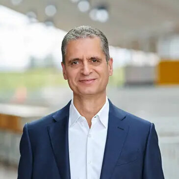 Portraitfoto von Rüdiger Kasch, Geschäftsführer von Alnatura; Mann gekleidet in weißem Hemd und blauem Sakko, im Hintergrund ist ein Firmengelände leicht verschwommeb erkennbar